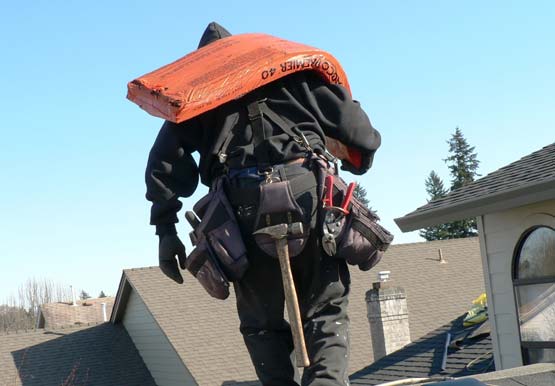 Shingles - Roofer Packing Shingles Across a Roof Installation